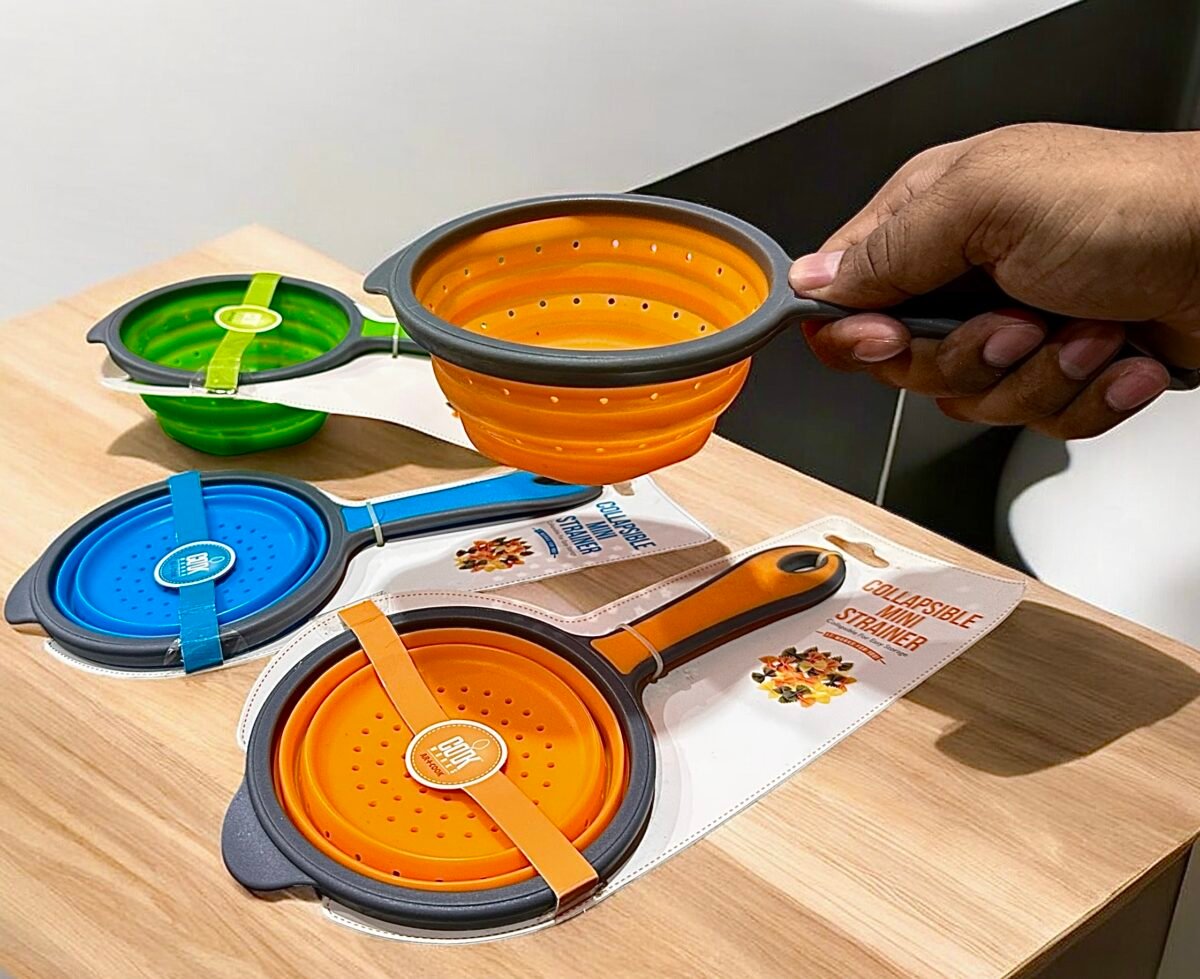 Collapsible silicone colander in green, orange, and blue, showing flexible, unbreakable design and quick drain holes for kitchen use.