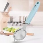Stainless steel fine mesh juice strainer with blue handle on a kitchen counter, perfect for straining juice, tea, or soup.