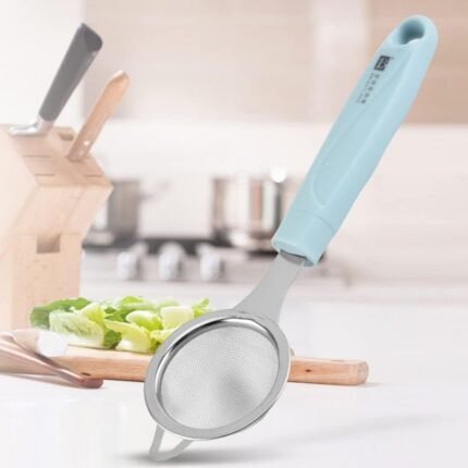 Stainless steel fine mesh juice strainer with blue handle on a kitchen counter, perfect for straining juice, tea, or soup.