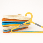 Stack of multi-color plastic hangers including yellow, blue, white, and orange for wardrobe organization