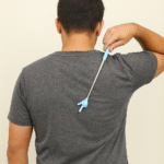 Man using a blue hand-shaped telescopic back scratcher stick for itching relief on his back