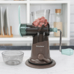 Danny Home manual meat grinder with hand crank and suction base filled with meat cubes on a kitchen counter