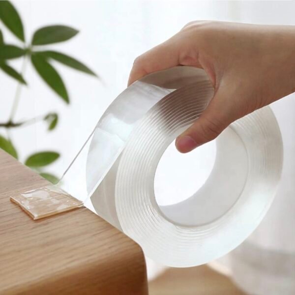 Hand using transparent Nano Magic Double-Sided Adhesive Tape on wooden surface – strong grip reusable tape for wall mounting and home use