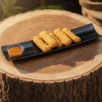 Black rectangular serving dish on wooden table – modern long platter for snacks, sushi, and appetizers, perfect for kitchen and restaurant use.