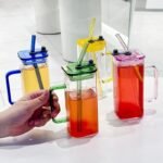 400ml square glass juice cup with colored handles and straws, durable household kitchen accessories available for wholesale rate in Pakistan.