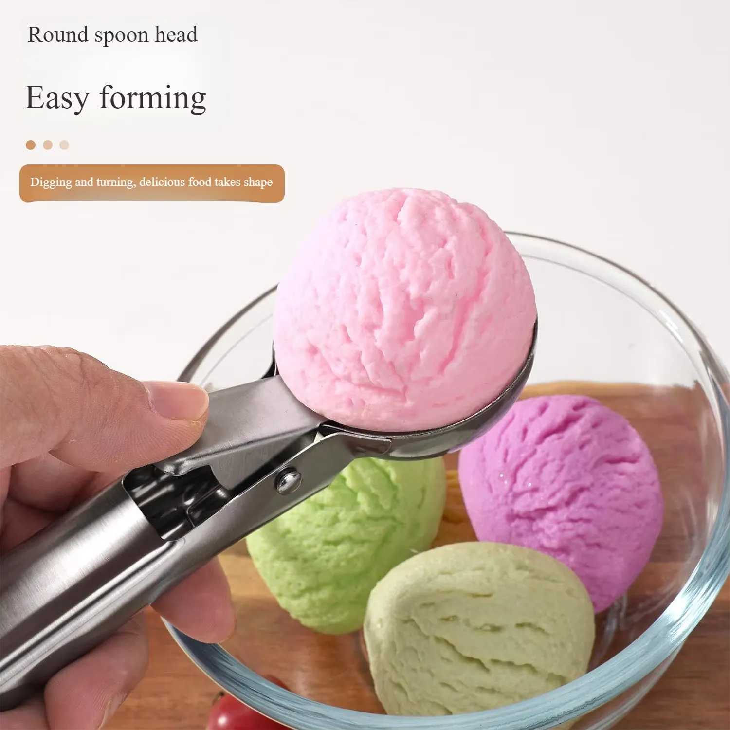 stainless-steel-ice-cream-scoop-pakistan.jpg Hand holding a stainless steel ice cream scoop with trigger release over a wooden table